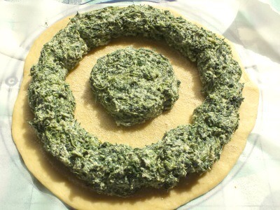 7. Distribute the filling on the circle that was just sprinkled with breadcrumbs. Place one large dollop at the center of the circle, and spread the remainder in a ring around the dough. See the picture below for reference.