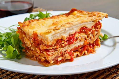 In a Dutch oven, cook sausage, ground beef, onion, and garlic over medium heat until well browned. Stir in crushed tomatoes, tomato paste, tomato sauce, and water. Season with sugar, basil, fennel seeds, Italian seasoning, 1 tablespoon salt, pepper, and 2 tablespoons parsley. 