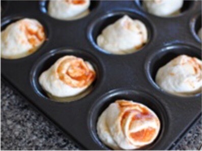 Cut up the roll into to smaller pieces and place each in the muffin tray, the swirl side facing up. Sprinkle the remaining shredded mozzarella on top and and a few pepperoni slices.