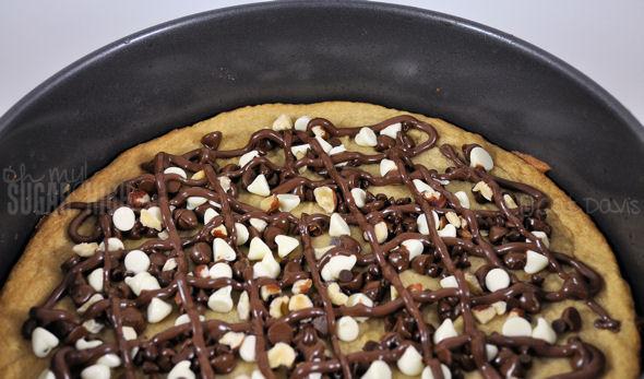 4. Sprinkle the baking chips evenly over the cookie, leaving the edges free so you’ll have a non chocolate surface to hold your pizza slice.

5. Using a piping bag (or use the corner of a plastic sandwich bag) spread the Nutella over the baking chips in any design you like.