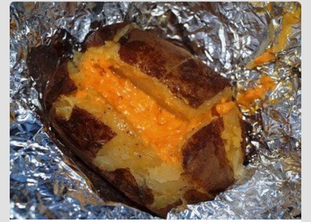 Pre-Bake Potatoes at home, cool, add shredded cheese and wrap in tin foil, reheat over the fire!